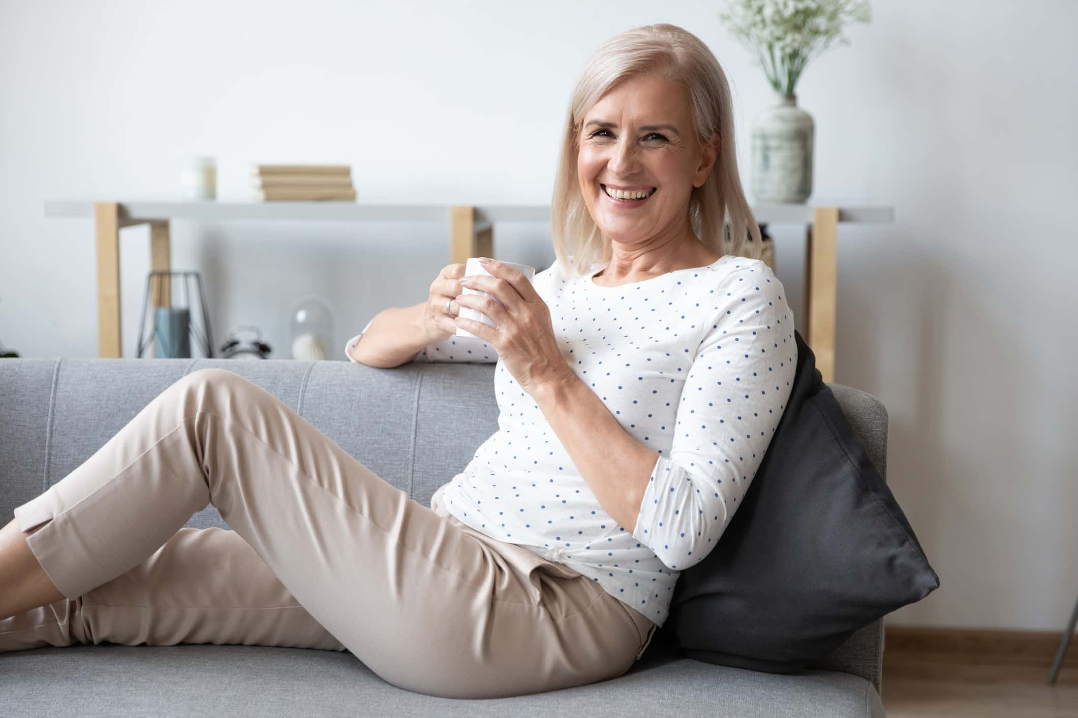 Portrait of smiling mature woman relaxing on couch with cup