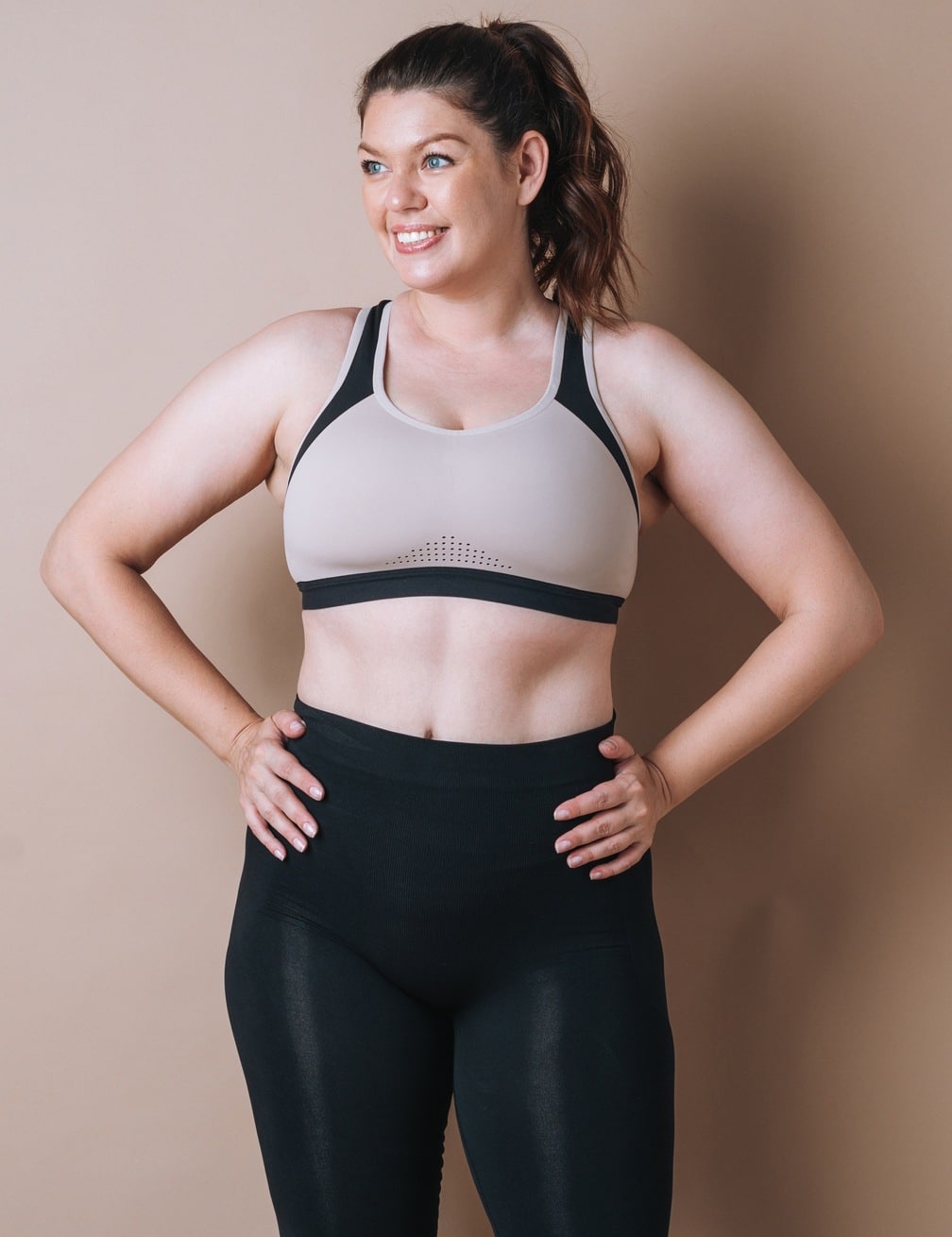 Self loving young woman plus size in sport wear on beige background, body love