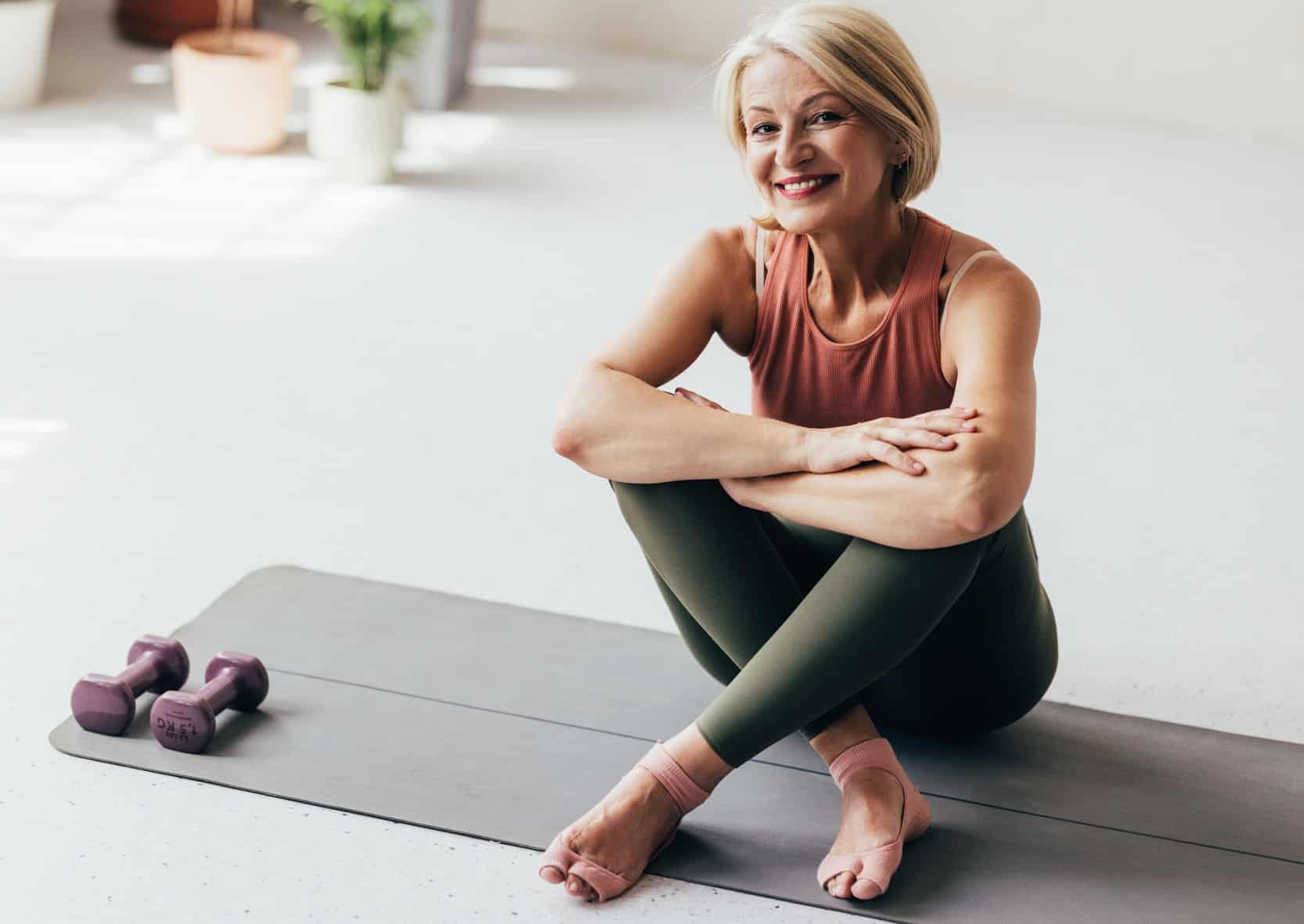 A Happy Blonde Senior Woman Looking At Camera After Doing Yoga At Home