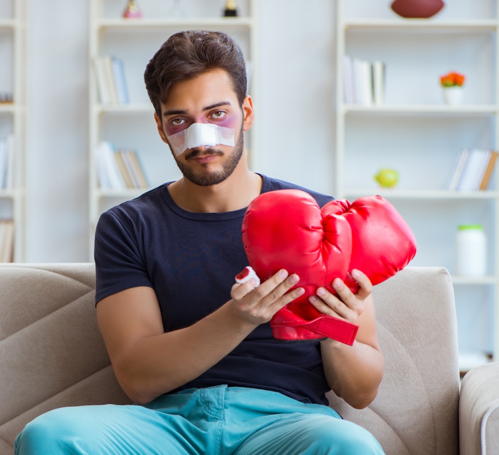 Man with bandage on nose holding boxing gloves, needing rhinoplasty in Salt Lake City, UT