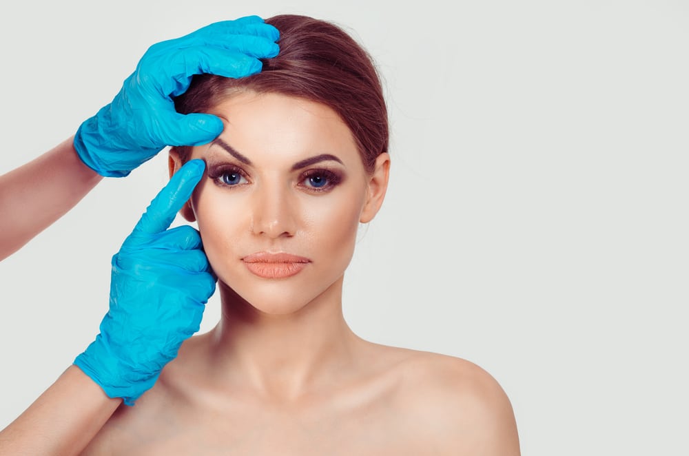 Surgeon lifting woman's brow with hand to prepare for brow lift surgery in Salt Lake City, UT