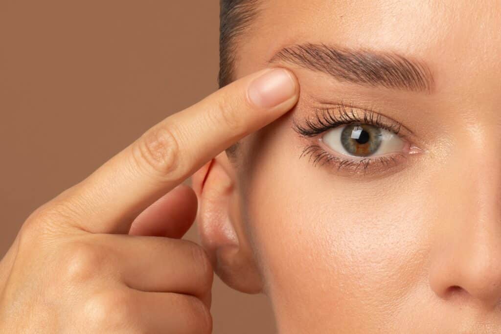 Woman pointing to her eyelid after blepharoplasty in Salt Lake City