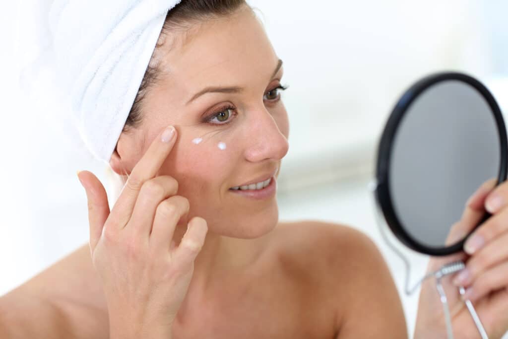 Woman looking in a mirror applying moisturizer after Morpheus8 treatment in Salt Lake City
