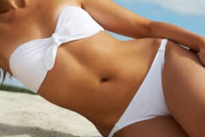 Close up of woman's midsection in a bikini after a tummy tuck or liposuction in Salt Lake City